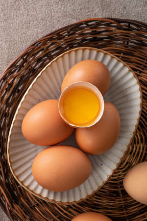 Top view of fresh brown chicken eggs in a plate on gray table background.