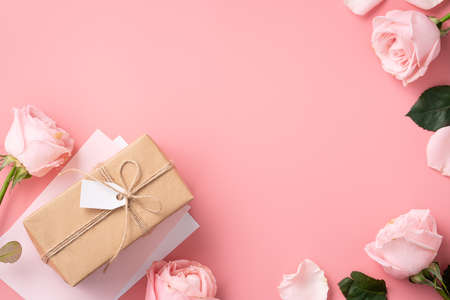 Floral design concept background with pink rose flower and wrapped kraft gift box on pink table background.の写真素材