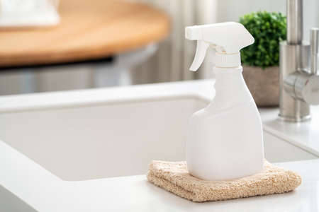 Concept of cleaning product spray bottle and rag in modern kitchen beside sink to wipe the counter...