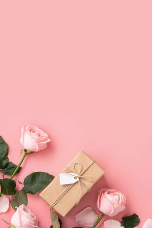 Mother's Day design concept background with pink rose flower and wrapped kraft gift box on pink table background.の写真素材