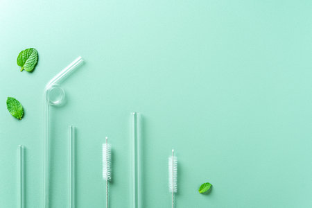 Reusable glass straw and cleaning brush set on green table background, design concept of environmental protection for Earth Day.の写真素材