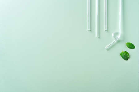 Reusable glass straw and cleaning brush set on green table background, design concept of...
