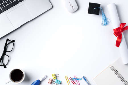 Top view of online learning and remote graduation ceremony commencement design concept with Graduation academic cap, diploma and laptop on white table background.の写真素材