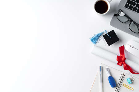 Top view of online learning and remote graduation ceremony commencement design concept with Graduation academic cap, diploma and laptop on white table background.の写真素材