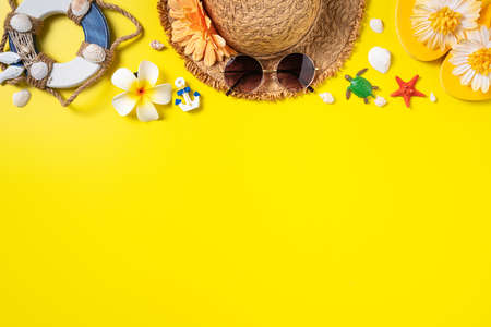 Summer beach design concept. Top view of holiday travel with shells, hat, slipper on yellow background.の写真素材