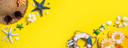 Summer beach design concept. Top view of holiday travel with shells, hat, slipper on yellow background.の写真素材