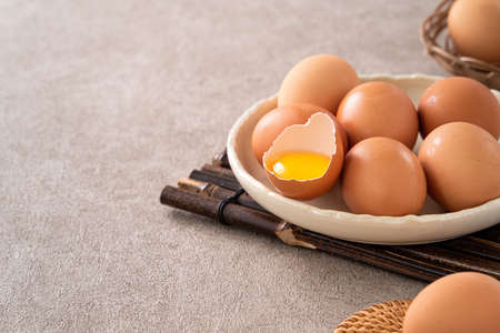 Top view of fresh brown chicken eggs in a plate on gray table background.