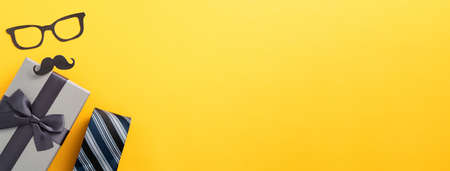 Father's day gift background design concept with gift box idea and necktie on yellow background.
