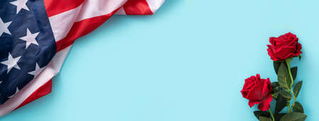 Concept of US Independence day or Memorial day. National flag over blue table background with red rose.の写真素材