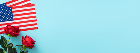 Concept of US Independence day or Memorial day. National flag over blue table background with red rose.の写真素材