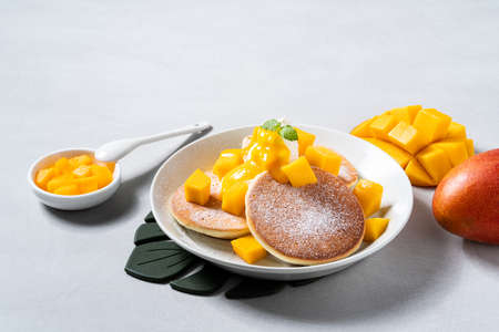 Delicious Japanese souffle pancake with dice mango fruit pulps and jam on white table background.の写真素材
