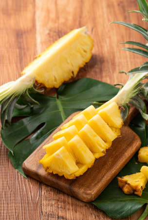 Close up of fresh cut pineapple on a tray over dark wooden table background.の写真素材