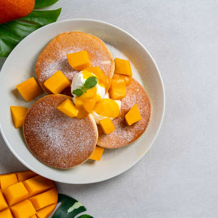Delicious Japanese souffle pancake with dice mango fruit pulps and jam on white table background.の写真素材