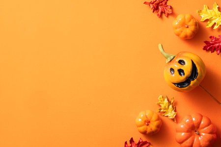 Creative Halloween design concept decoration on orange paper table background with pumpkin, autumn leaves and copy spaceの写真素材