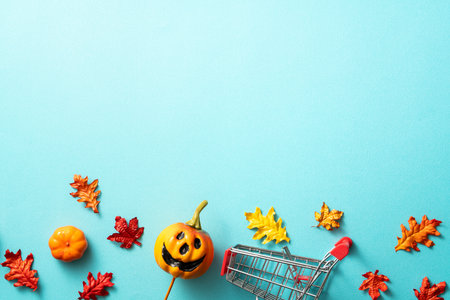 Creative Halloween autumn shopping design concept decoration on blue paper table background with pumpkin, autumn leaves and copy spaceの写真素材