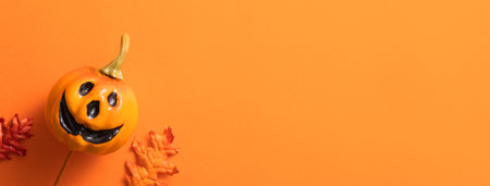 Creative Halloween design concept decoration on orange paper table background with pumpkin, autumn leaves and copy spaceの写真素材
