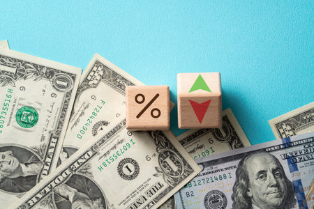 Wooden blocks with interest rate percent of bank with US dollars, financial world economy crisis design concept over blue table background.の写真素材