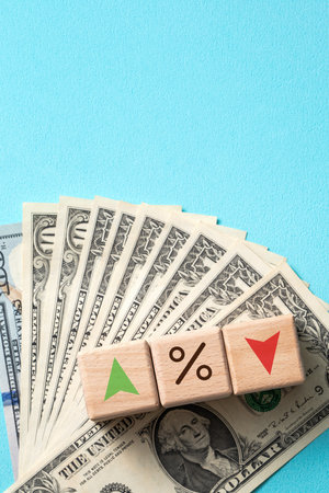 Wooden blocks with interest rate percent of bank with US dollars, financial world economy crisis design concept over blue table background.の写真素材