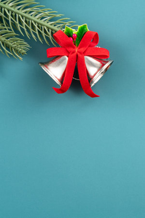 Christmas background design concept, holiday decoration ornament composition with Christmas tree branch, golden bell with copy space isolated on green table.の写真素材