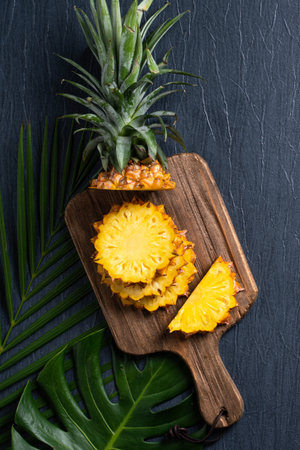 Top view of fresh cut pineapple with tropical leaves on dark blue background.の写真素材