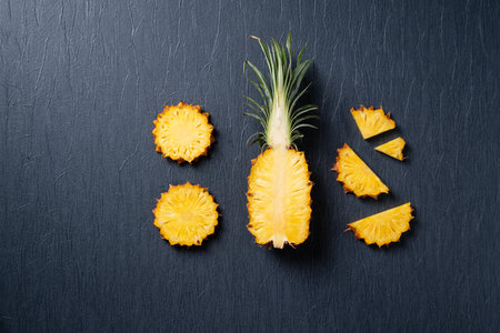 Top view of fresh cut pineapple with tropical leaves on dark blue background.の写真素材