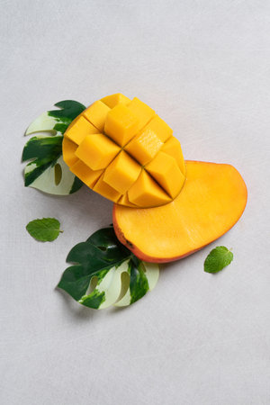 Mango background design concept. Top view of diced fresh mango fruit pattern with leaves on gray table.の写真素材