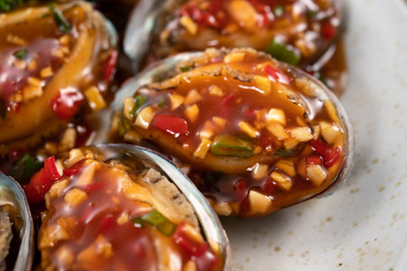Delicious steamed abalone with spicy tomato sauce, Taiwanese five flavor sauce on wooden table background.の写真素材