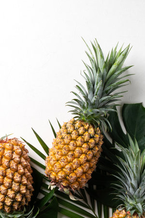 Top view of fresh pineapple with tropical monstera leaves on white background.の写真素材