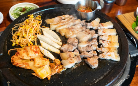 Pan-fried black pork meal in Jeju Korean restaurant, fresh delicious korean food cuisine on iron plate with lettuce, kimchi, banchan and sauce, lifestyle.の写真素材