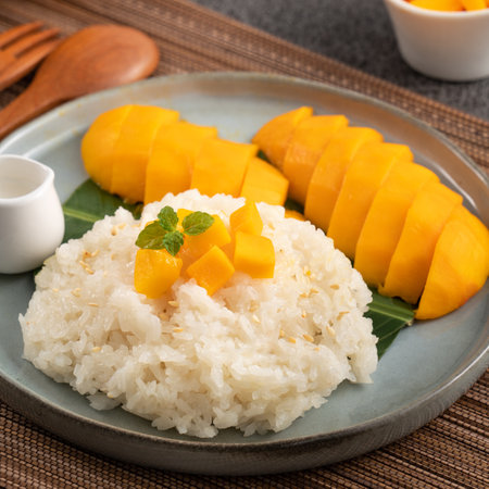 Delicious Thai mango sticky rice with cut fresh mango fruit in a plate on gray table background.の写真素材