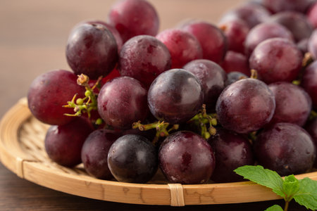 Delicious bunch of purple grapes fruit on a tray over wooden table background.の写真素材