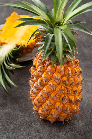 Fresh cut sliced juicy pineapple in a plate over dark gray table background.の写真素材