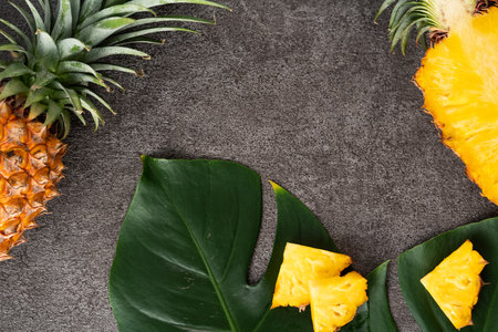 Top view of fresh cut pineapple with tropical leaves on dark gray table background.の写真素材