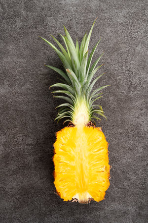 Top view of fresh cut pineapple with tropical leaves on dark gray table background.の写真素材