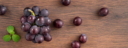 Delicious bunch of purple grapes fruit spilled over wooden table background.の写真素材