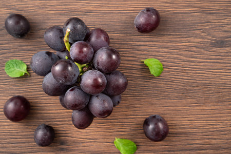 Delicious bunch of purple grapes fruit spilled over wooden table background.の写真素材