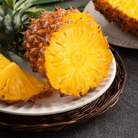 Fresh cut sliced juicy pineapple in a plate over dark gray table background.の写真素材