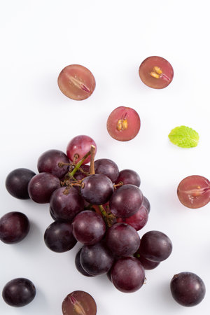 Delicious bunch of purple grapes fruit spilled over white table background.の写真素材