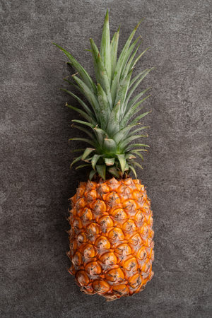 Top view of fresh cut pineapple with tropical leaves on dark gray table background.の写真素材