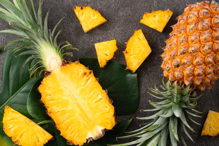 Top view of fresh cut pineapple with tropical leaves on dark gray table background.の写真素材