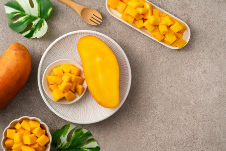 Fresh chopped, diced mango cubes on gray table background with tropical leaf for eating.の写真素材