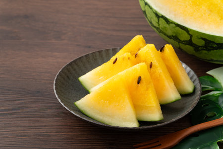 Sliced yellow golden watermelon in a plate on wooden table background ready for eating.の写真素材