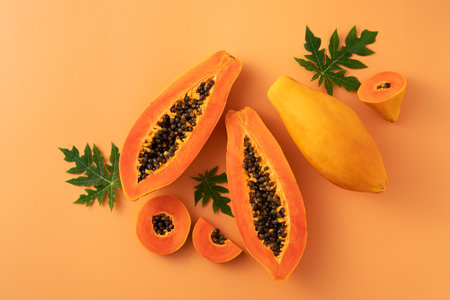 Cut Papaya over orange table background for tropical fruit design concept, top view copy space.の写真素材