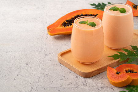 Fresh delicious papaya milk smoothie in glass cup on gray table background for tropical fruit design concept.の写真素材