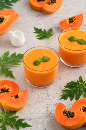 Fresh delicious papaya milk smoothie in glass cup on gray table background for tropical fruit design concept.の写真素材