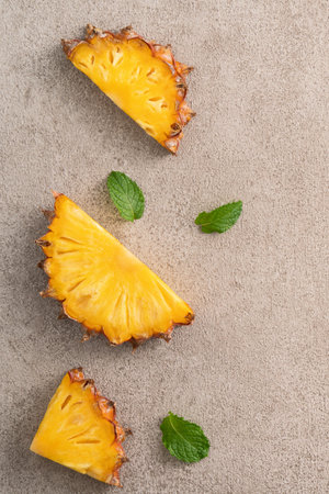 Top view of fresh cut pineapple with tropical leaves on gray table background.の写真素材