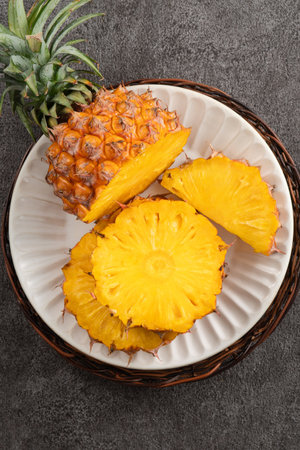 Top view of fresh cut pineapple with tropical leaves on gray table background.の写真素材