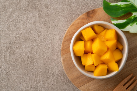 Fresh chopped, diced mango cubes on gray table background with tropical leaf for eating.の写真素材