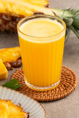 Fresh delicious pineapple juice smoothie, cold drink in glass cup on gray table background.の写真素材