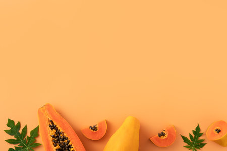 Cut Papaya over orange table background for tropical fruit design concept, top view copy space.の写真素材